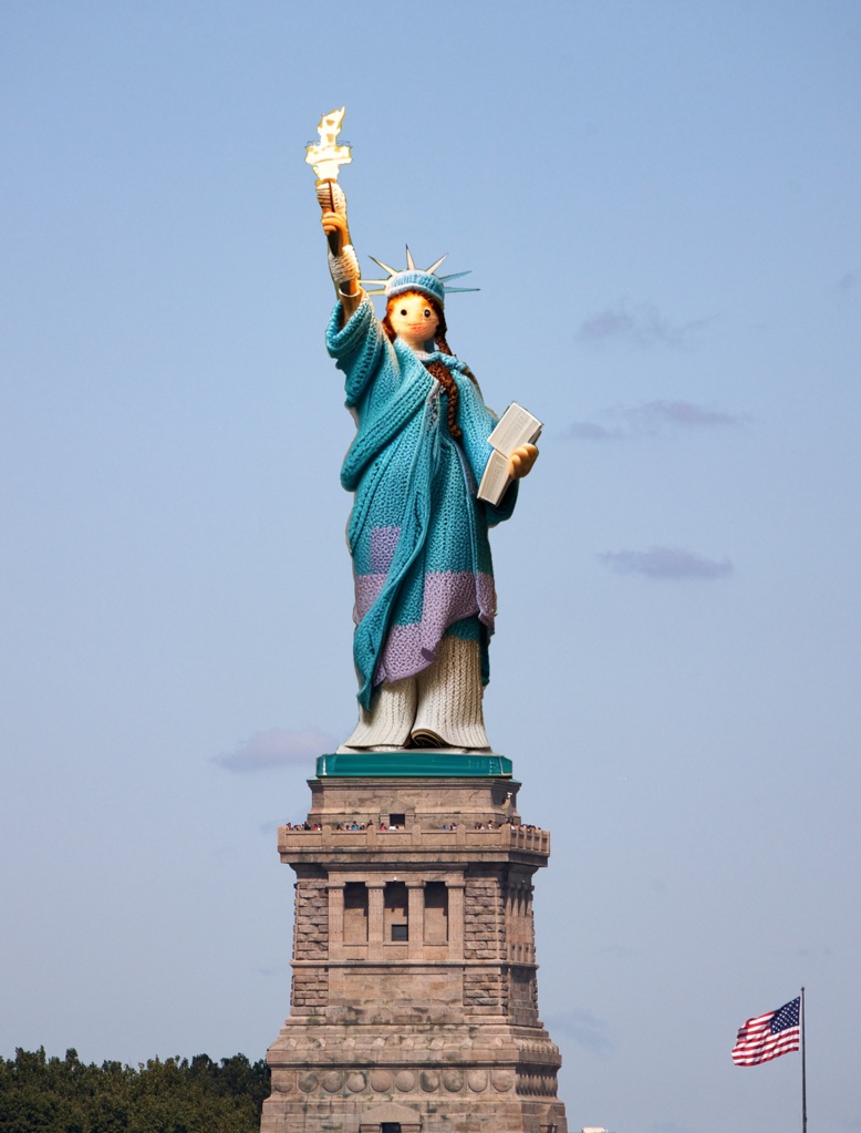 An icon taken from the Hudson River when she was caught by a beam of sunlight .; [Amigurumi] a lady holding a torch in one hand, and a book on another hand, day time